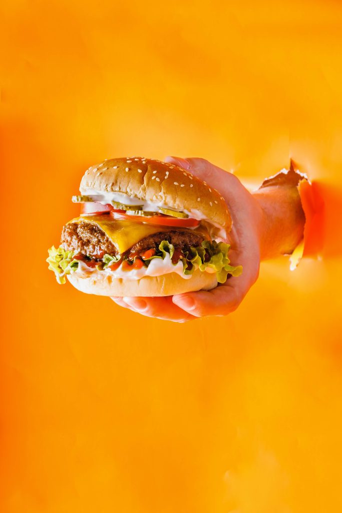 Dies ist ein Werbebild für einen Burger mit einem Monochromen Hintergrund.